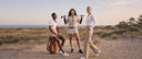 Three women wearing Crossover Golf luxury women’s golf apparel, including polos, skorts, trousers, and windbreakers, on a coastal golf course. Chic golf apparel for women of all sizes and ages for on and off the course. 
