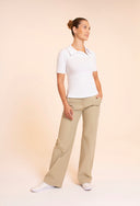 High-waisted women’s golf trousers with tailored straight-leg fit and 4-way stretch, chic golf outfit designed for on and off the course. Crossover Golf apparel. Crossover Golf New Classic Polo, tailored women’s golf polo with asymmetric placket and ultra-soft micromodal fabric, styled as a chic golf outfit for modern country club style on and off the course