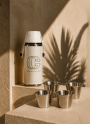 Crossover Golf Pour Four Flask Set with white vegan leather flask, four stainless steel shot glasses, and filling funnel on travertine stone. Golf flask set. Mini flask set. Luxury flask set. Chic flask set