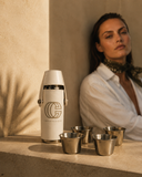 Crossover Golf Pour Four Flask Set with white vegan leather flask, four stainless steel shot glasses, and filling funnel on travertine stone. Golf flask set. Mini flask set. Luxury flask set. Chic flask set