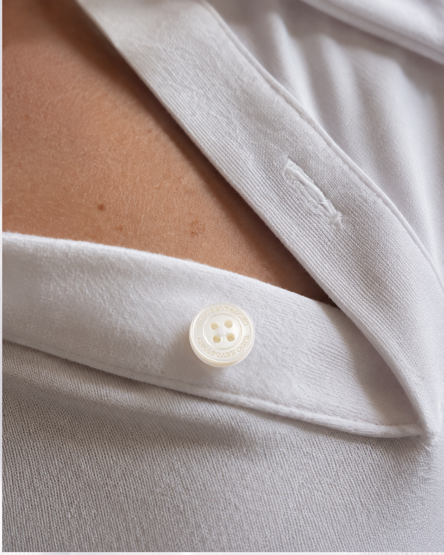 Shell button and refined placket detailing on a white Crossover Golf women's polo.